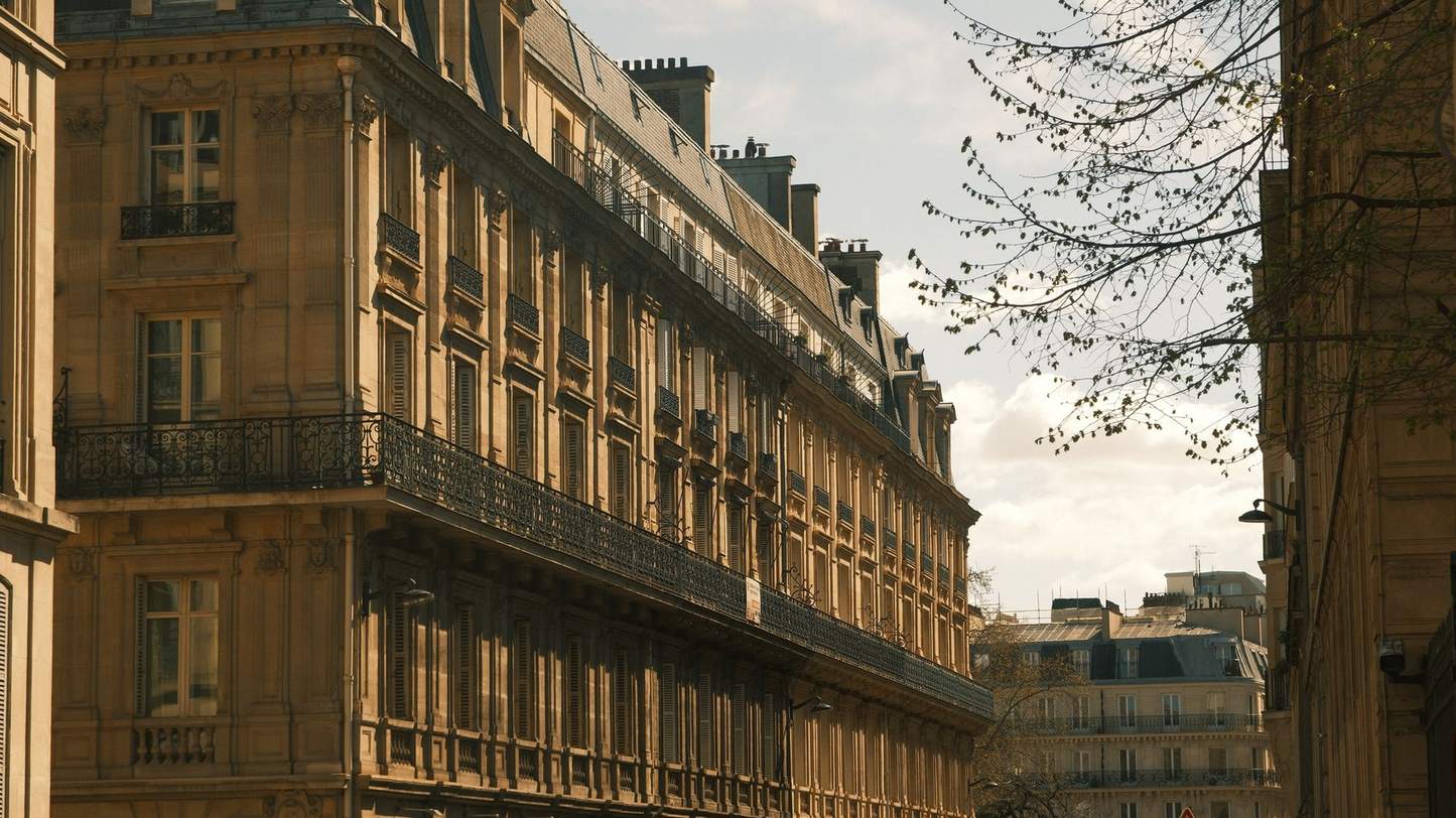 Façade en pierre d'un immeuble de rapport : balcons filants, fenêtres à petits carreaux
